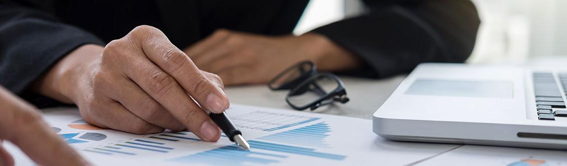 Photo of hands of an accountant doing calculations with document graph, digital tablet and laptop computer